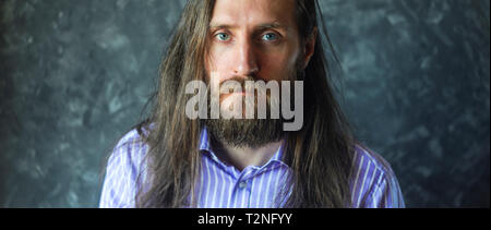 Mode Portrait eines bärtigen Mann im gestreiften Formale Shirt mit Langen fließenden Haar. Informelles Konzept. Filmische Erntegut Stockfoto