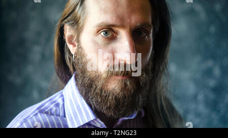 Mode Portrait eines bärtigen Mann im gestreiften Formale Shirt mit Langen fließenden Haar. Informelles Konzept Aussehen Stockfoto