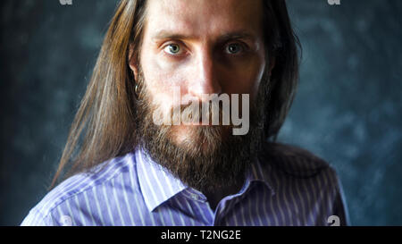 Mode Portrait eines bärtigen Mann im gestreiften Formale Shirt mit Langen fließenden Haar. Informelles Konzept Aussehen Stockfoto