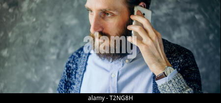 Der bärtige Mann auf ein Handy mit Gleichgültigkeit. Schwierige Telefonat Konzept Stockfoto