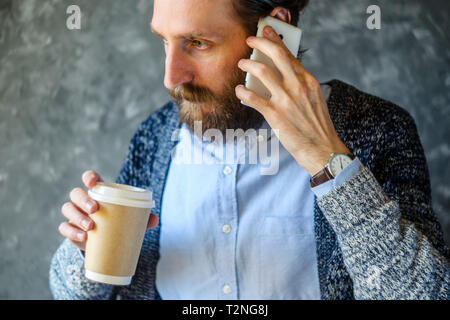 Der bärtige Mann auf ein Handy mit Gleichgültigkeit. Schwierige Telefonat Konzept Stockfoto