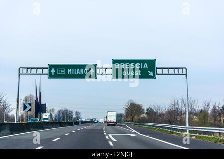 Grüne Hinweisschild nach Milano und Brescia über Licht blauer Himmel Stockfoto