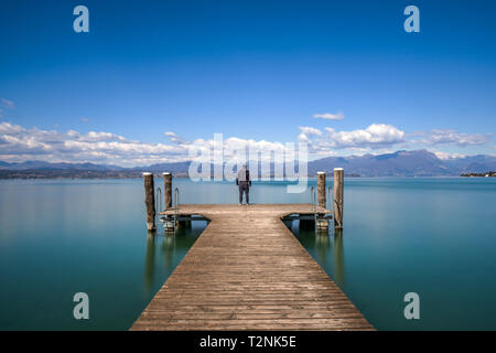 Man steht auf einem Steg von ruhigen Gardasee, Italien Stockfoto