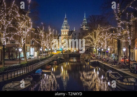 Schöne beleuchtete Bäume säumen die Gracht in Amsterdam das "Venedig des Nordens", die sich auf eine niederländische Geschichte museum Rijksmuseum in Amsterdam, Net führt Stockfoto