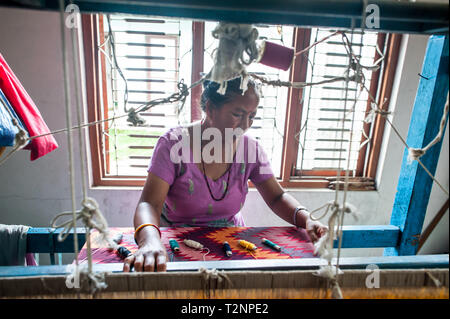 Ein Nepali Frau sticken Seide und Wolle pashmina Schals von Webstuhl, W.F. Nepal, eine nichtstaatliche Organisation, die Beschäftigung von marginalisierten Frauen auf einer gleichberechtigten Basis. Stockfoto