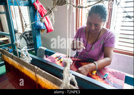 Ein Nepali Frau sticken Seide und Wolle pashmina Schals von Webstuhl, W.F. Nepal, eine nichtstaatliche Organisation, die Beschäftigung von marginalisierten Frauen auf einer gleichberechtigten Basis. Stockfoto