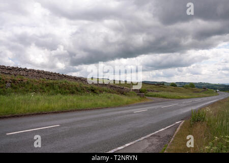 Die B6282 Straße in Middleton in Teesdale im Nordosten von England zeigen die urbares Land und dunkle Vorahnung Himmel Stockfoto