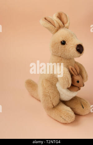 Soft Toy mom Känguruh mit Baby ist auf einem Pfirsich Hintergrund entfernt, vertikale Foto Stockfoto
