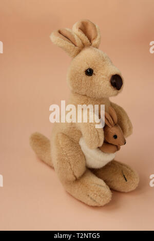 Soft Toy mom Känguruh mit Baby ist auf einem Pfirsich Hintergrund entfernt, vertikale Foto Stockfoto