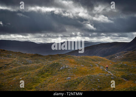 Männliche biker Biken auf Feldweg in der Berglandschaft, Rückansicht, Addo, Scottish Highlands, Schottland Stockfoto