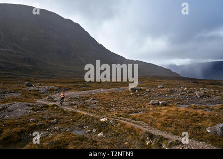 Männliche biker Biken auf Feldweg in Berg Tal Landschaft, Rückansicht, Addo, Scottish Highlands, Schottland Stockfoto