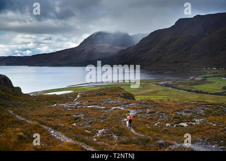 Männliche biker Biken auf Feldweg in Berg Tal Landschaft, Rückansicht, Addo, Scottish Highlands, Schottland Stockfoto