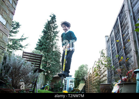 Junge springen auf Pogo stick im Garten Stockfoto