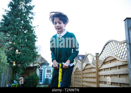 Junge springen auf Pogo stick im Garten Stockfoto