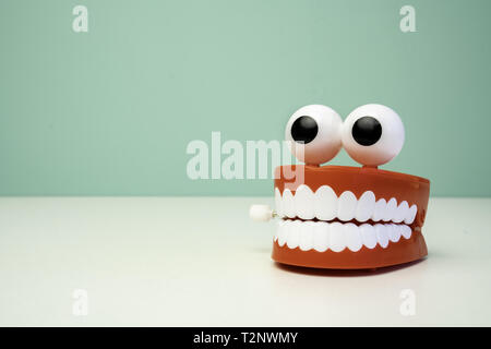 Das Klappern der Zähne Spielzeug auf einem Tisch mit einem grünen Hintergrund. Kiefer lustig Zähne Stockfoto