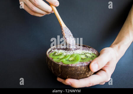 Gesunde Smoothie mit Obst, Platte aus Kokosnussschalen und Holz Löffel. Kiwi, Banane, Schwarze Johannisbeere Stockfoto