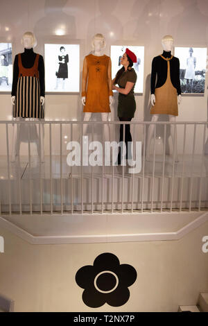 Ein Mitglied des Personals in einem Quant Kleid passt ein Display Modell in der Ausstellung 'Mary Quant', die sich im Victoria und Albert Museum, London, Erscheinen öffnet sich Stockfoto