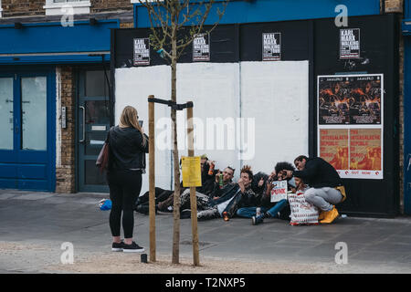 London, UK - März 23,2019: Frau unter Foto von Punks posieren für ein Foto auf einer Straße in Camden Town, London, einem Gebiet, berühmt für seine Markt- und nightli Stockfoto