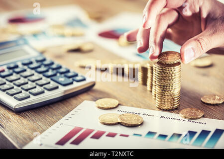 Womans hand Euro Münzen mit einem Wachstum Wirkung. Stillleben mit business plan cackulator und Euro Währung. Stockfoto