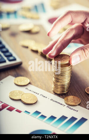 Womans hand Euro Münzen mit einem Wachstum Wirkung. Stillleben mit business plan cackulator und Euro Währung. Stockfoto