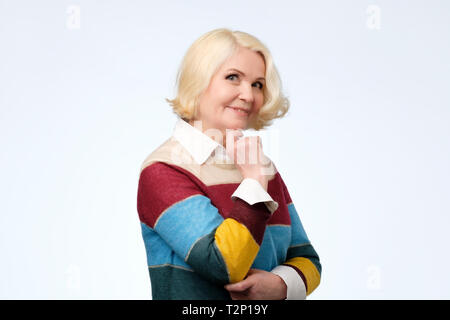 Lächelnde ältere Frau mit blonden Haaren an Kamera schaut zuversichtlich. Positiven menschlichen Gesichts emotion Stockfoto