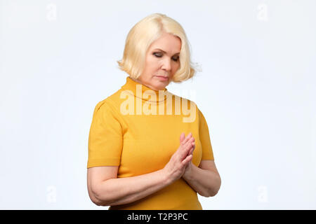 Trauriger Alter ältere Frau in gelber Kleidung nach unten schauen. Negative facial Emotion Stockfoto