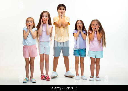 Das Porträt von glücklich süße kleine Kinder, Junge und Mädchen in stilvollen legere Kleidung bei Kamera gegen Weiße studio Wand. Kids Fashion und menschliche Emo Stockfoto