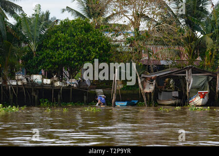 Can Tho, Vietnam - am 31. Dezember 2017. Eine Frau wäscht Kleidung in einer Wasserstraße auf der Rückseite ihres Hauses im Mekong Delta Stockfoto