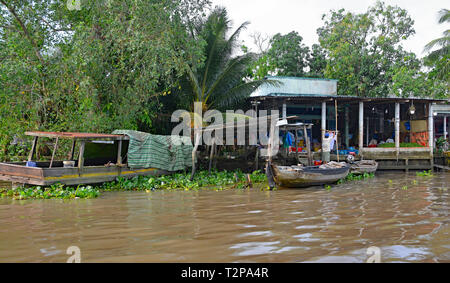 Can Tho, Vietnam - am 31. Dezember 2017. Ein Mann legt auf einem T-Shirt in seinem Haus, über das Sie auf die Wasserstraße im Mekong Delta sieht zu trocknen Stockfoto