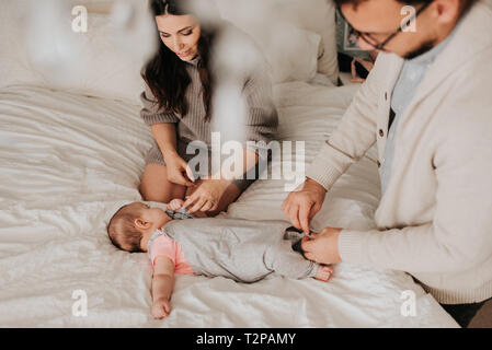 Paar dressing baby Tochter auf dem Bett im Schlafzimmer Stockfoto