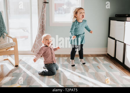 Weibliche Kleinkind und Baby Bruder spielen auf Wohnzimmer Teppich Stockfoto