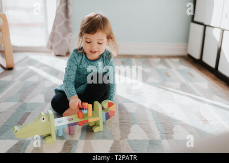 Weibliche Kleinkind spielen mit Spielzeug auf Wohnzimmer Teppich Stockfoto