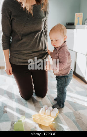 Mutter Knien in Wohnzimmer mit Baby Sohn Stockfoto
