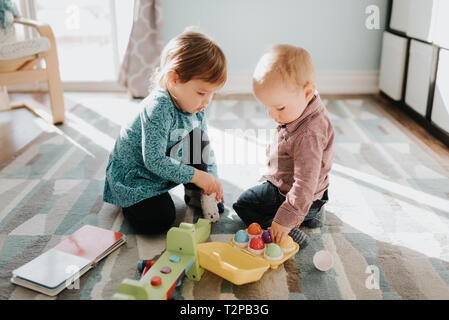 Weibliche Kleinkind spielen mit Baby Bruder im Wohnzimmer Stockfoto