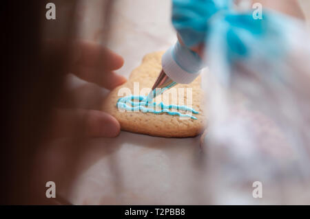 Kind Hände spielen mit Lebkuchen und farbigen Glasur Stockfoto