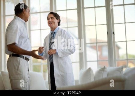 Freundlich im mittleren Alter Arzt hören ein älterer Patient sprechen. Stockfoto