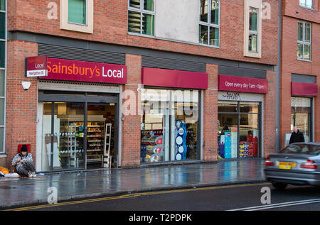 Birmingham, England - 17. März 2019: ein Obdachloser sitzt am Eingang zu örtlichen Sainsbury's Supermarkt auf Navigation Straße Stockfoto