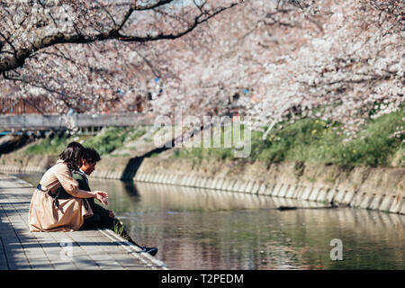 Ein paar gesehen genießen während der iwakura Cherry Blossom Festival einen Höhepunkt der Bogen um rund 1.400 Cherry Blossom Bäume, die an beiden Ufern des Gojo Fluss, der fließt durch Iwakura Stadt gepflanzt wurden erstellt. Stockfoto