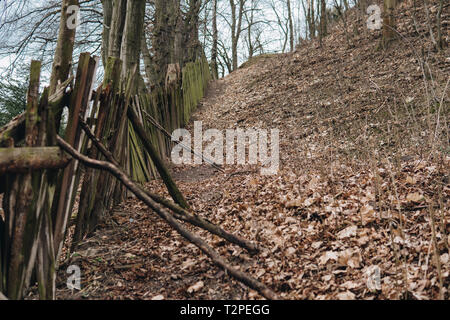 Hügel mit einem Wiegenden alten hölzernen Zaun mit Moos im Herbst abgedeckt Stockfoto