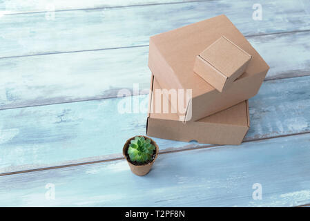 Drei unterschiedlich große Schachteln und grüne Pflanze auf einem Topf im Büro selektiven Fokus Stockfoto