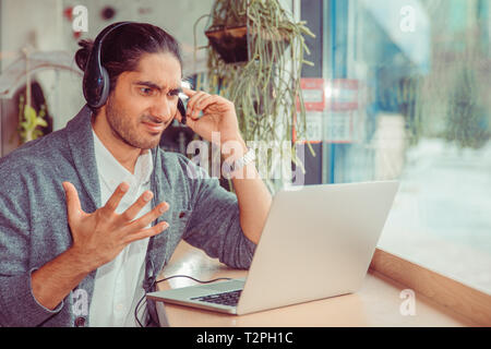 Call Center Mitarbeiter im Büro auf der Suche nach Laptop frustriert. Closeup Portrait eines türkischen hübscher Kerl tragen formalen weißes Hemd und Grau bl Stockfoto