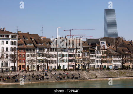Blick auf Basel, Innenstadt und Rhein. Von alten Gebäuden, Cafés und moderne Wolkenkratzer. Menschen sitzen, die von der Bank. Blue Sky. Stadtbild. Schweiz Stockfoto