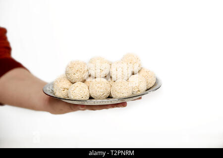 Bild des Menschen Hand cholai ke ladoo in der Platte. Auf den weißen Hintergrund isoliert. Stockfoto