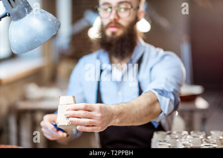 Gut aussehender bärtiger Mann arbeiten mit keramischen Werkstücken am Arbeitsplatz der Töpferei shop Stockfoto