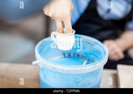 Malerei Tonkrüge, tauchen in den Eimer mit der blauen Farbe, Nahaufnahme Stockfoto
