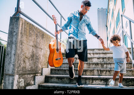 Vater die Gitarre und Halten der Sohn hand auf Treppe Stockfoto