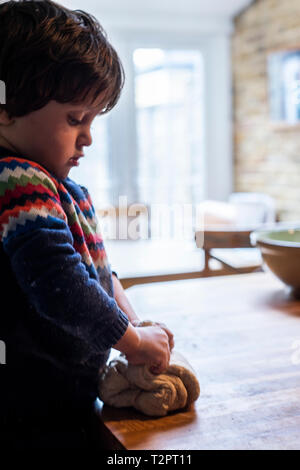 Kleinkind kneten den Teig auf die Küchenarbeitsplatte Stockfoto