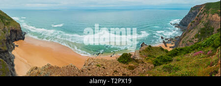 Sandstrand mit felsigen Bergrücken trübes Wetter Aussicht auf Sommer Atlantic an der felsigen Küste (Costa Vicentina, Algarve, Portugal). Und Ocean Surf Wellen. Stockfoto