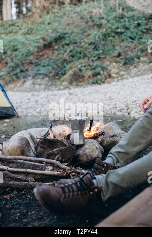 7/8 outdoor Bild des jungen Mannes explorer sitzen in der Nähe von bonfire warme Getränke in den Bergen. Konzept Abenteuer aktiv Urlaub. Sommer ca Stockfoto