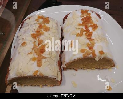 Zwei Mandel Kuchen auf weiße Platte mit in Scheiben geschnittenen getrockneten Früchten, Lasur- und Eisbildung auf der Oberseite Stockfoto